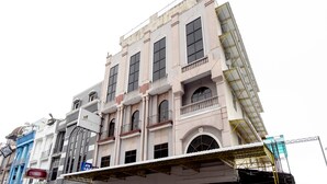 Un edificio de varios pisos con amplios ventanales y balcones, que presenta una combinación de estilos arquitectónicos.