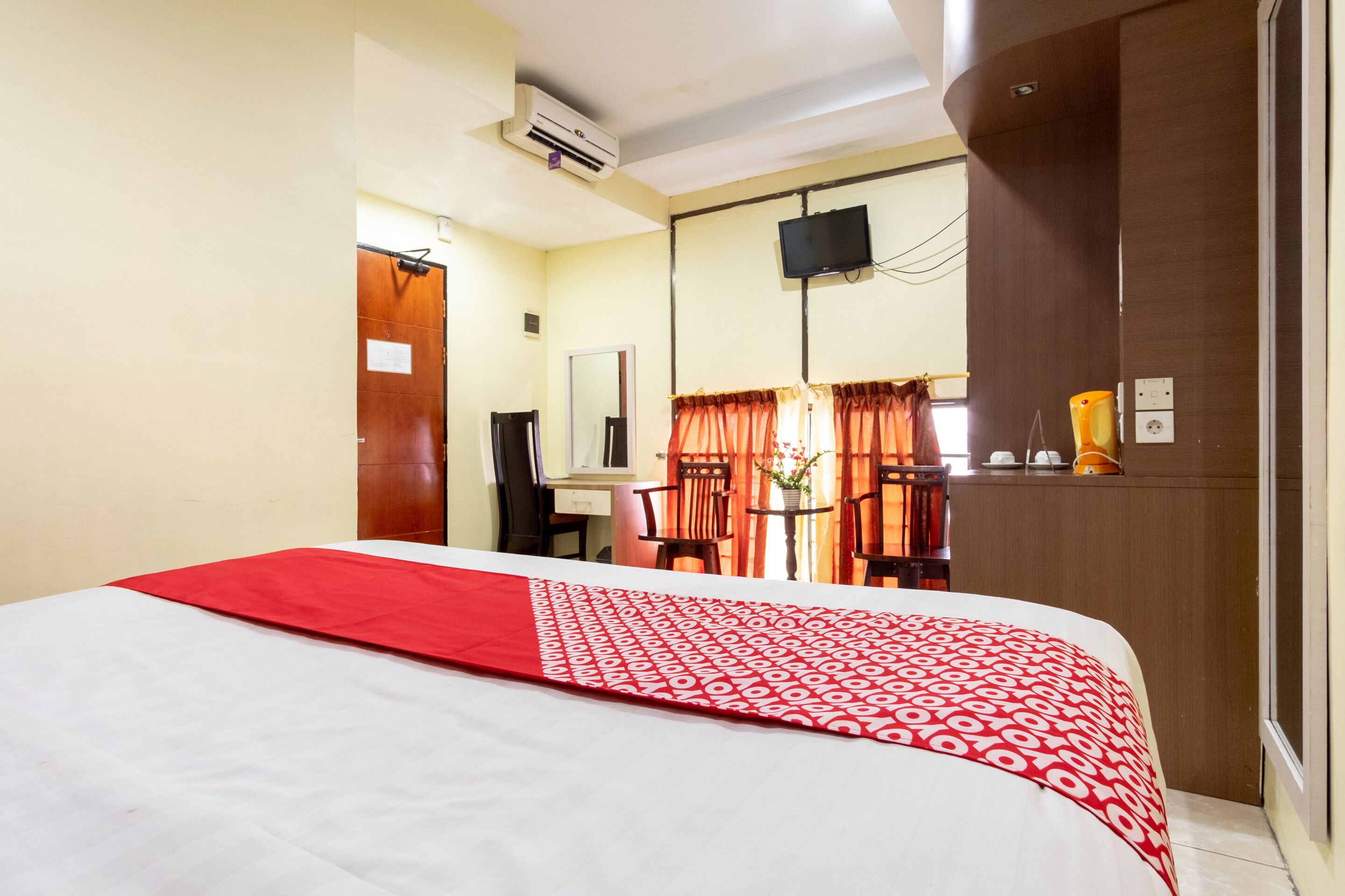 A hotel room with a bed, a desk, a chair, a television, and a window with curtains.