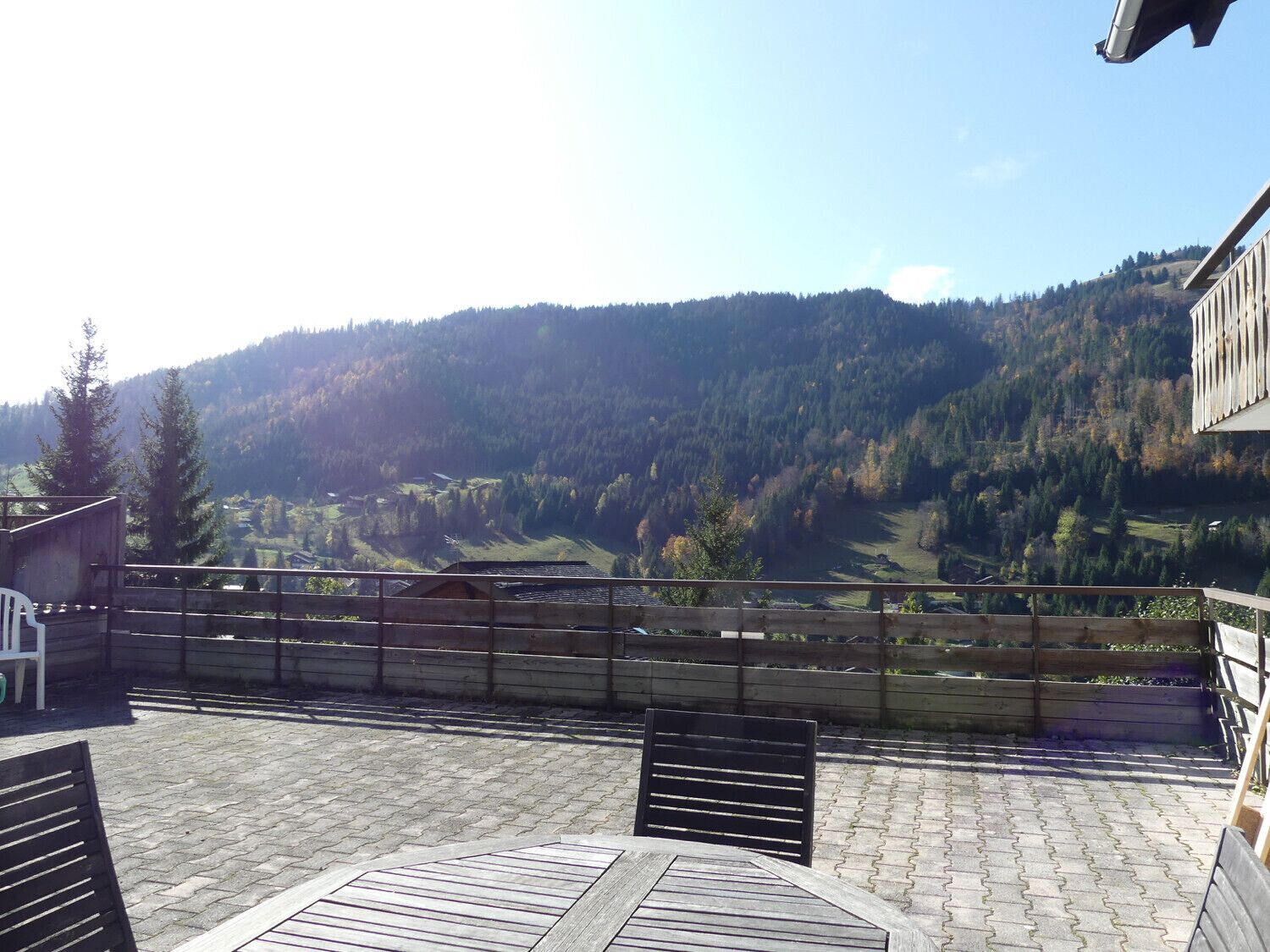 A terrace with a view of a valley and forested hills.