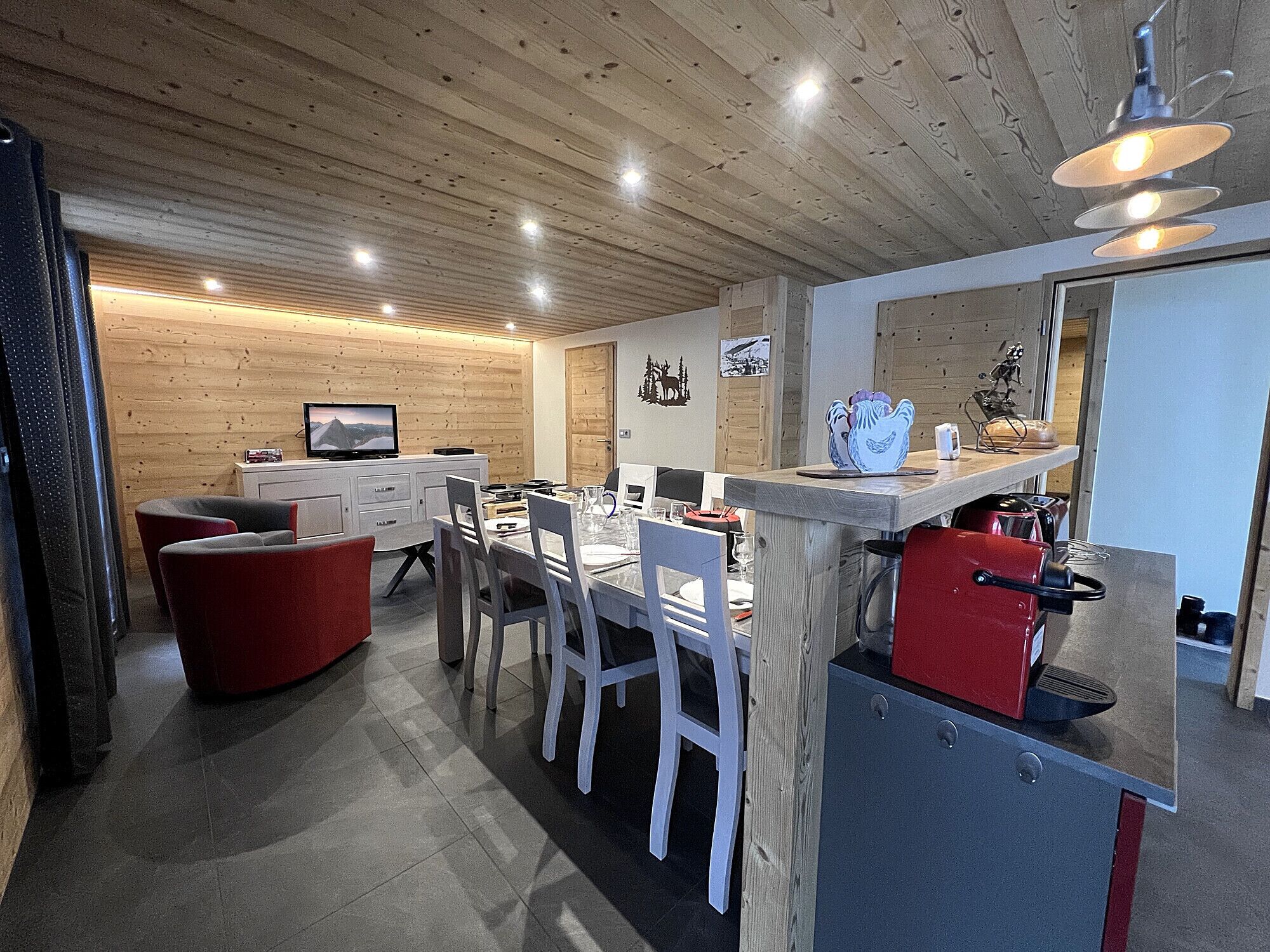 Een moderne keuken met een houten plafond, een eethoek met witte stoelen, en een rode apparatuur.