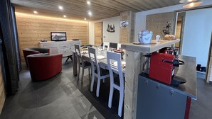 Een moderne keuken met een houten plafond, een eethoek met witte stoelen, en een rode apparatuur.