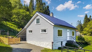 A single-story house with a sloped roof, a front porch, and a gravel driveway. - 2 bedroom stunning home in Flekkefjord (Flekkefjord)