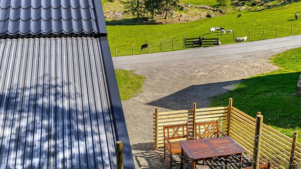 A view of a rural landscape with a fenced area, a wooden bench, and a metal roof. - 2 bedroom stunning home in Flekkefjord (Flekkefjord)