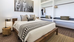 Quarto moderno com uma cama grande, uma mesinha de cabeceira, prateleira na parede com roupas e uma obra de arte emoldurada acima da cama.