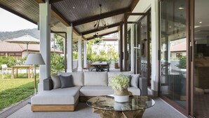 Um espaço de estar moderno ao ar livre, com uma mesa de centro de vidro, um sofá modular bege e uma mesa de centro de madeira.