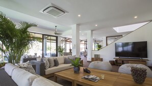 Uma sala de estar moderna com uma grande TV de tela plana, assentos confortáveis e uma planta grande.