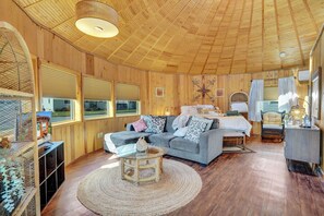 L’intérieur chaleureux d’un chalet avec un plafond en bois, un canapé, un lit et une table à manger.