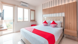 Een hotelkamer met een bed, televisie, raam en balkon.