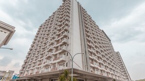 Een hoog appartementencomplex met meerdere balkons en een modern architectuur.