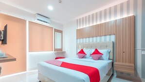 Een moderne hotelkamer met een groot bed, een houten hoofdbord en een ingebouwde televisie.