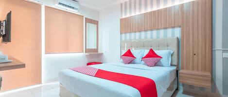 A modern hotel room with a large bed, a wooden headboard, and a built-in TV.