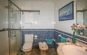 A bathroom with a glass shower enclosure, a toilet, a bidet, a sink, and a mirror with a painting. - 1 bedroom beautiful apartment in Santa Pola (Santa Pola)