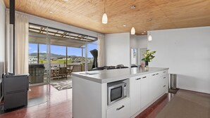 A modern kitchen with a large island, stainless steel appliances, and a view of the outdoors.