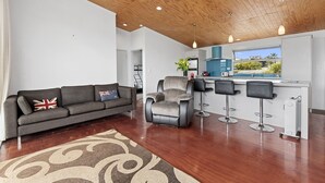 A modern living room with a sofa, a recliner, and a bar area with stools.