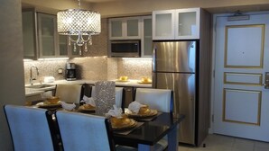 A modern kitchen with a dining table set for four, stainless steel appliances, and a decorative chandelier.