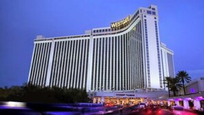 A high-rise hotel with a prominent "WESTCHALL" sign, featuring a modern architectural design with vertical lines and a flat roof.