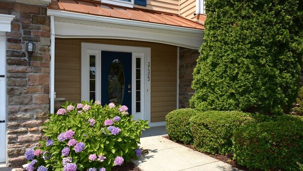 A house with a stone facade, a front door, and a well-maintained garden with hydrangea bushes. - Spacious Townhouse Amenity Rich Rehoboth Beach (Rehoboth Beach)
