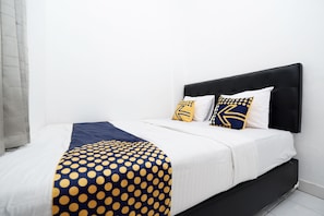 A neatly made bed with a white and navy blue bedspread, two matching pillows, and a navy blue polka dot throw blanket. - OYO Life 1942 Asia Residence Syariah (Semarang)