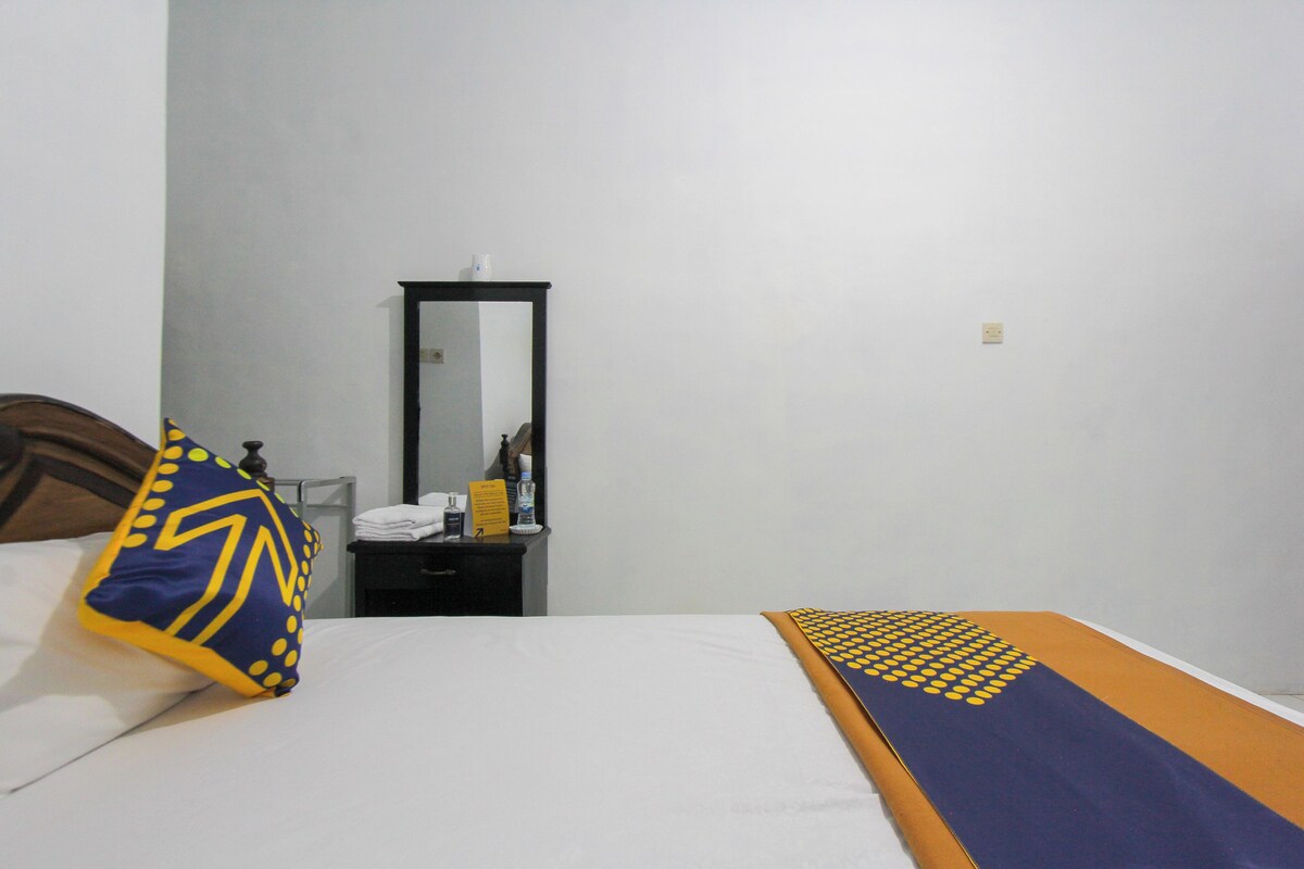 Une chambre d’hôtel équipée d’un lit, d’une table de chevet, d’un miroir et d’une prise électrique murale.