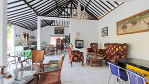 Ein geräumiges Zimmer mit hoher Decke, einem Chandelier und einem Essbereich mit Holzmöbeln.