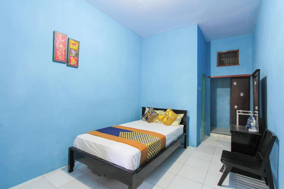 A bedroom with a bed, a bench, and a door leading to another room.