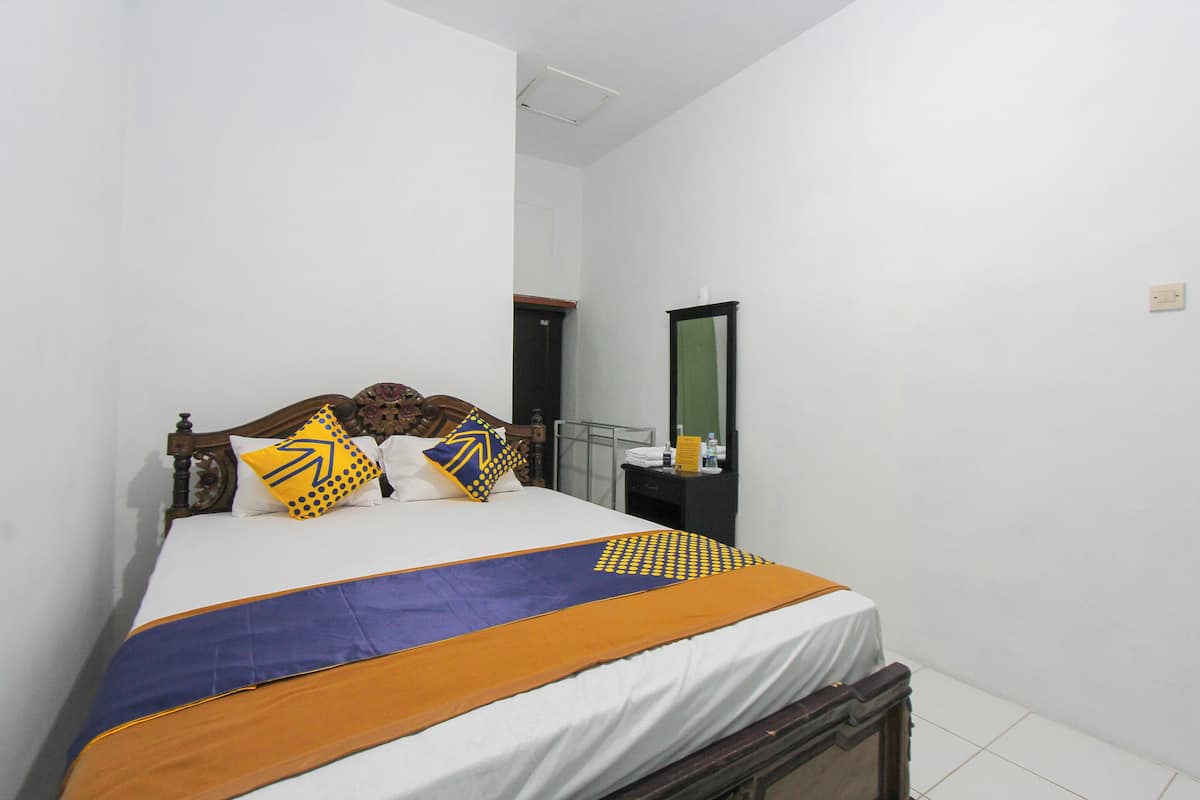 A bed with a patterned bedspread, a wooden headboard, and two pillows with a geometric design.