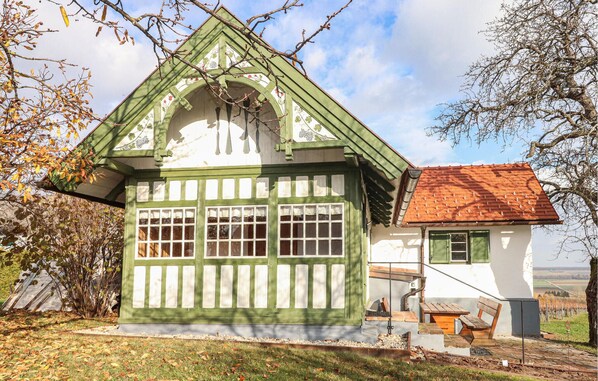 Ett traditionellt hus med en grön och vit fasad, ett rött tegeltak och en liten veranda med träbänkar.