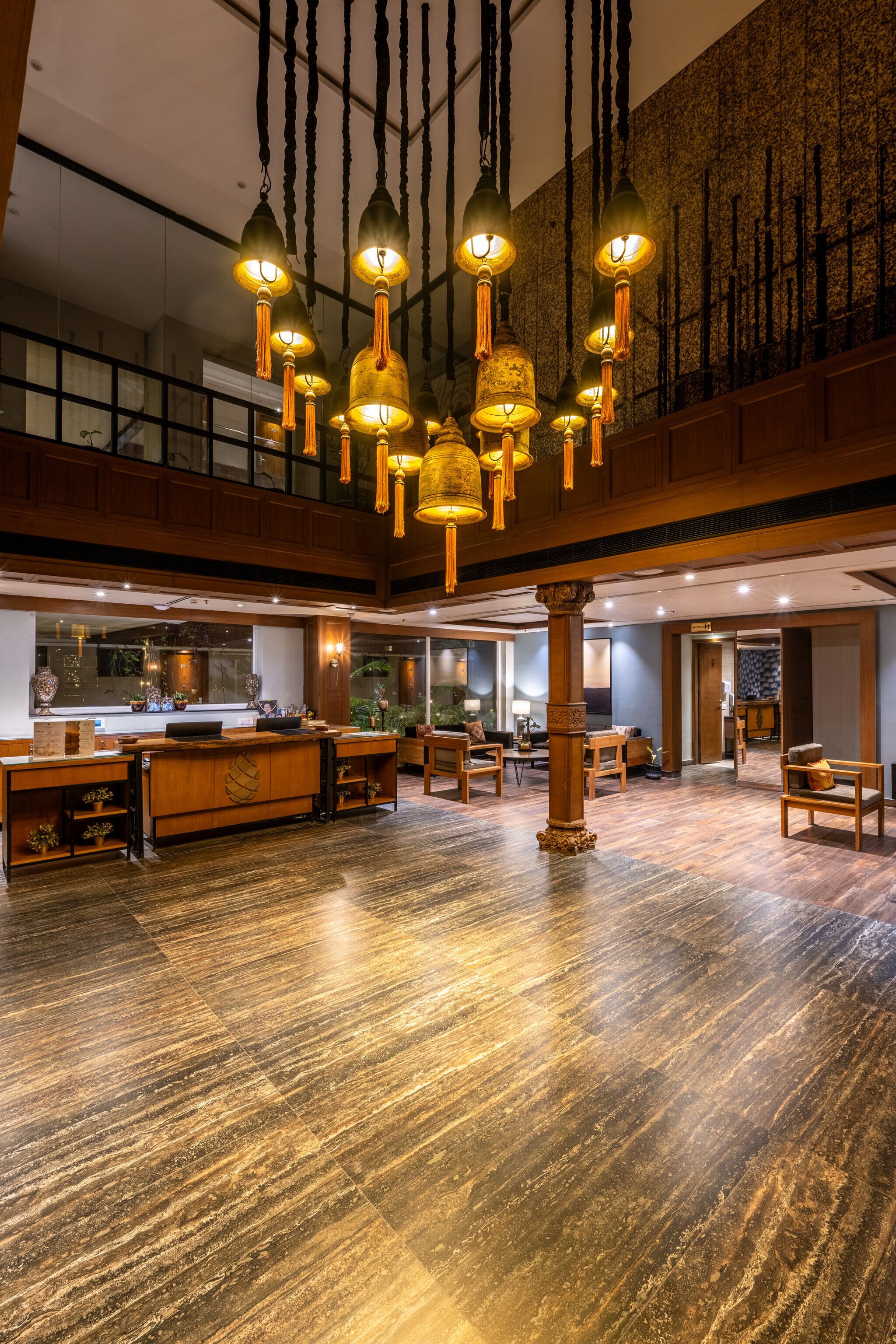 Un'ampia hall con una reception in legno, lanterne appese e un pavimento in legno lucidato.