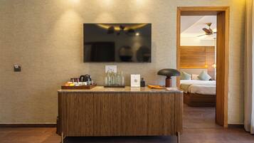 Una habitación de hotel moderna con un mostrador de recepción de madera, un televisor de pantalla plana montado en la pared y una cama con cabecero de madera.