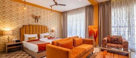 A hotel room with a bed, two sofas, a coffee table, and a TV.