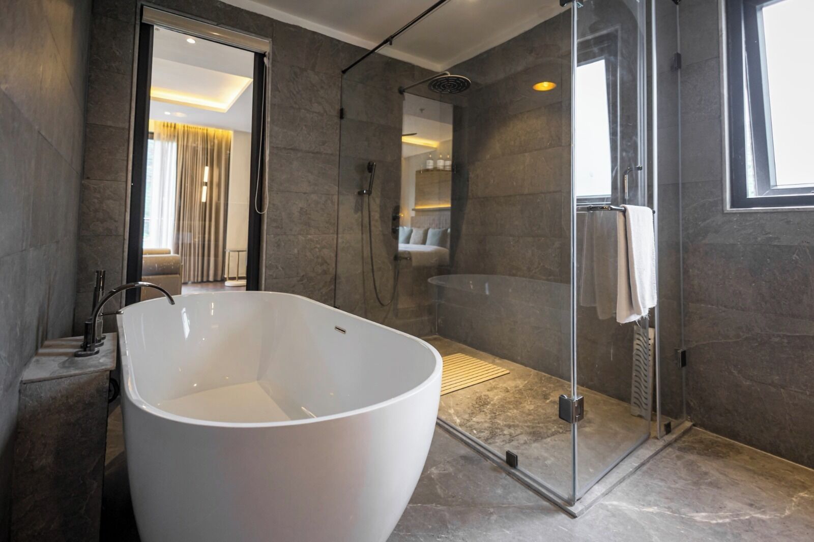 Een moderne badkamer met een vrijstaand bad, een glazen douchecabine en een grote spiegel.