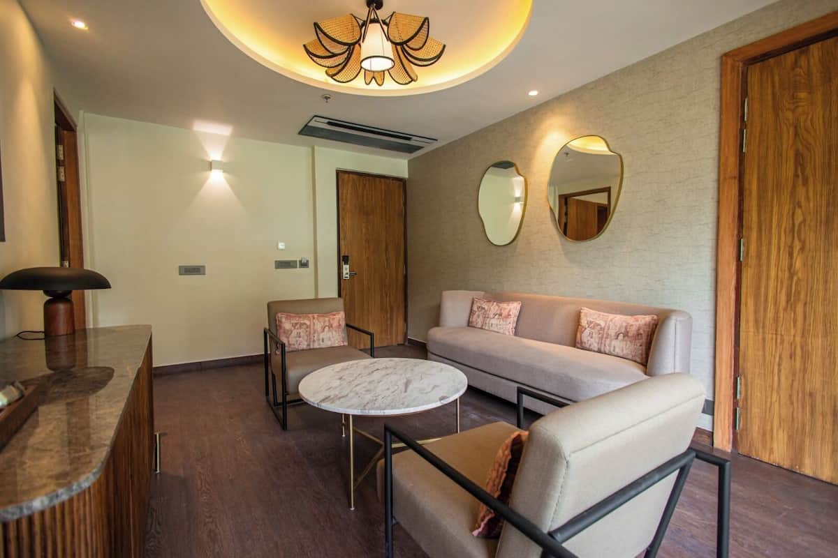 A modern hotel room with a marble coffee table, a sofa, and a desk with a lamp.