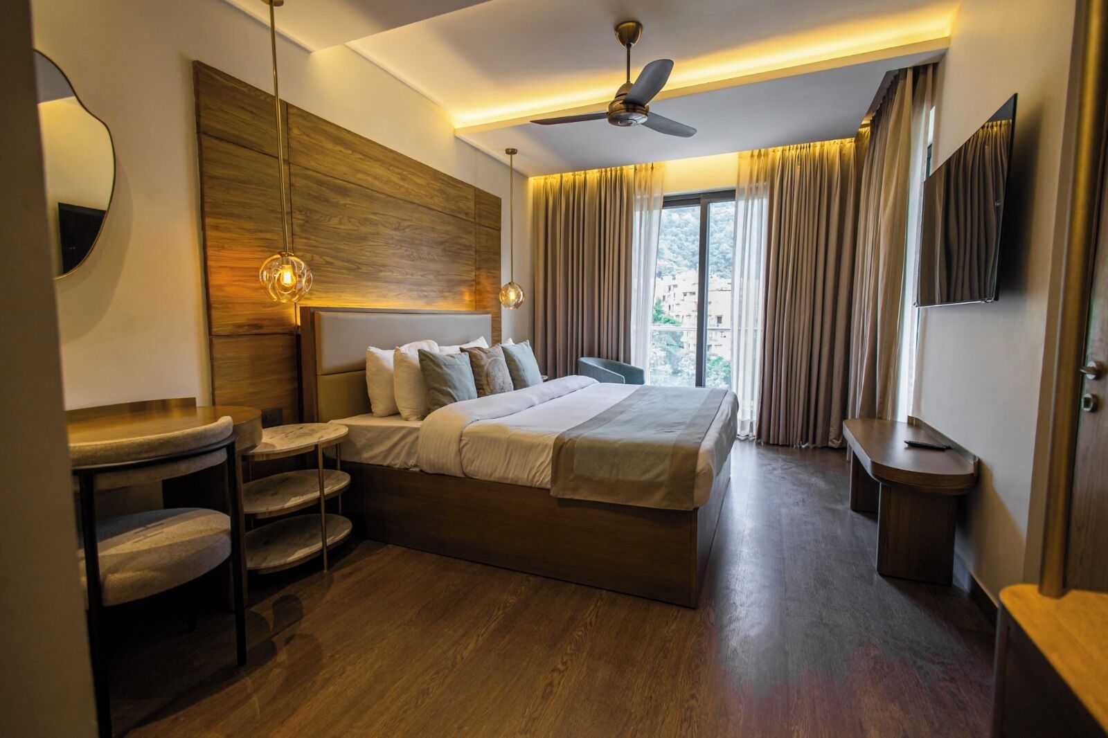 Une chambre d’hôtel moderne, dotée d’un grand lit, d’un bureau et d’un ventilateur de plafond.