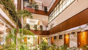 Un atrio de varios niveles con un jardín de rocas central, plantas en macetas y paneles de madera.