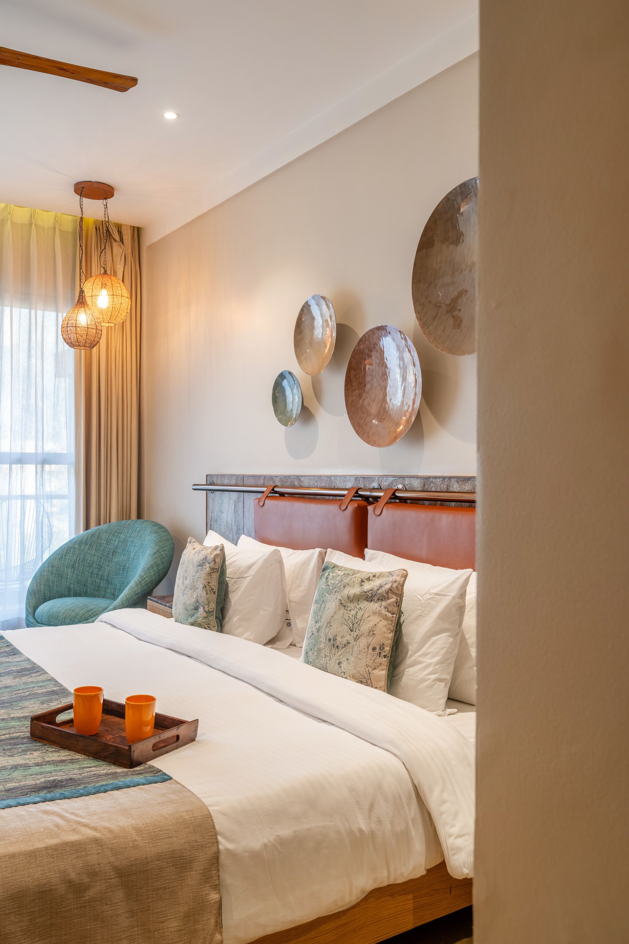 A hotel room with a bed, a wooden headboard, a green chair, and decorative wall plates.