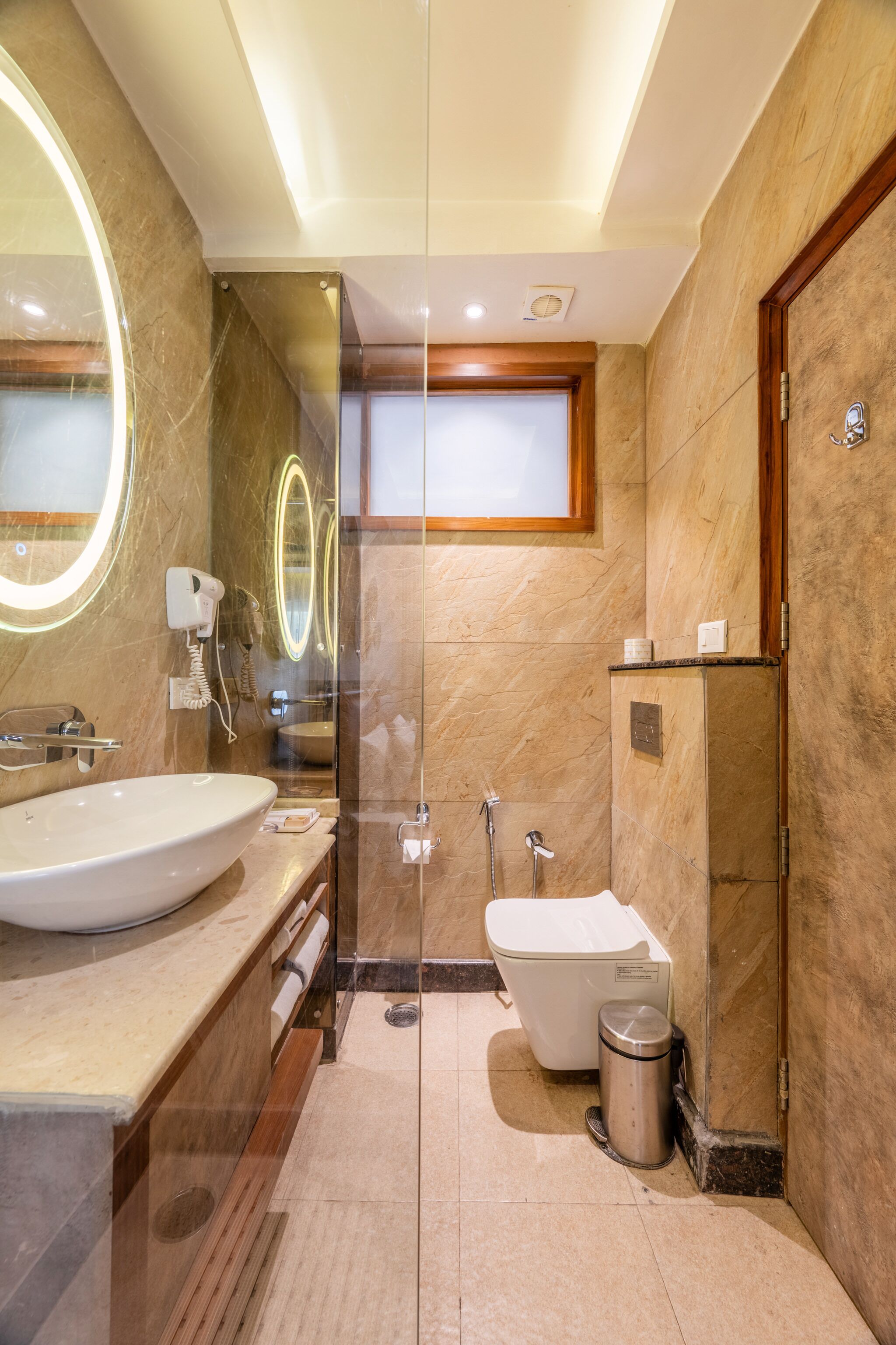 A modern bathroom with a large sink, a glass-enclosed shower, and a toilet.