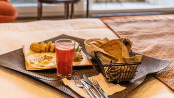 Ein Frühstückstisch mit Essen, einem Glas roten Saft und einem Brotkorb.