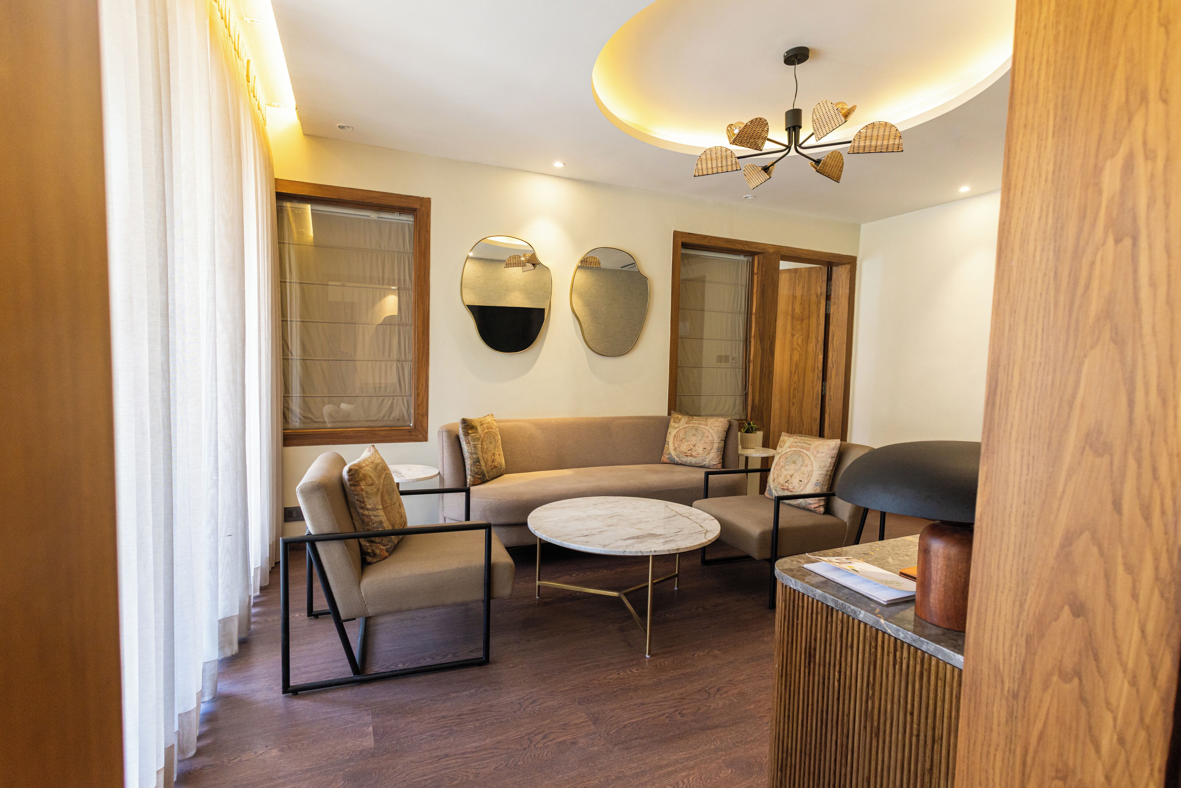 A modern living room with a sofa, armchairs, a coffee table, and a unique ceiling light fixture.