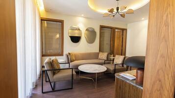 A modern living room with a sofa, armchairs, a coffee table, and a unique ceiling light fixture.