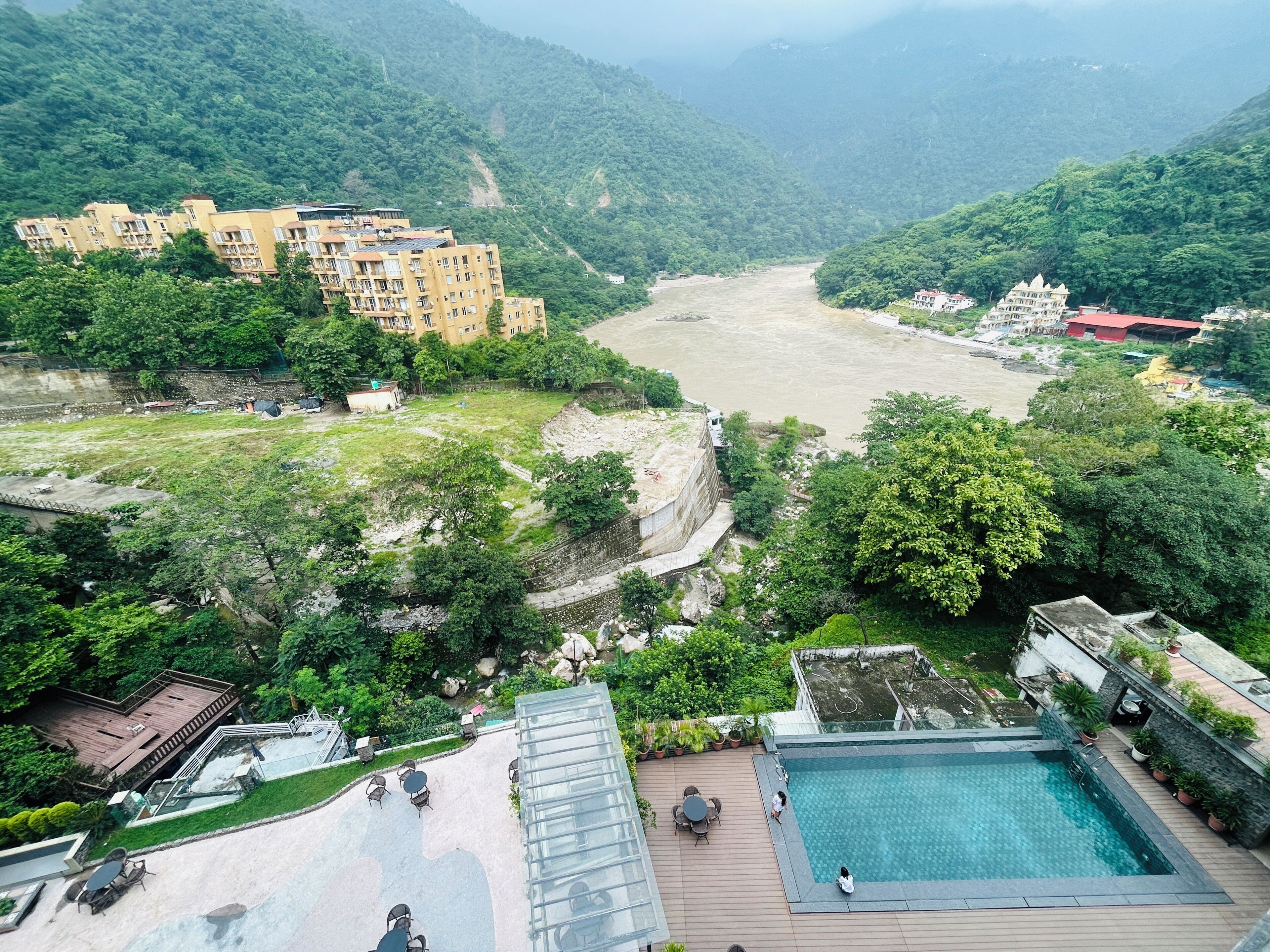 A hotel with a swimming pool, outdoor seating, and a view of a river.
