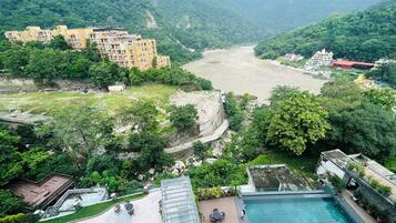 A hotel with a swimming pool, outdoor seating, and a view of a river.