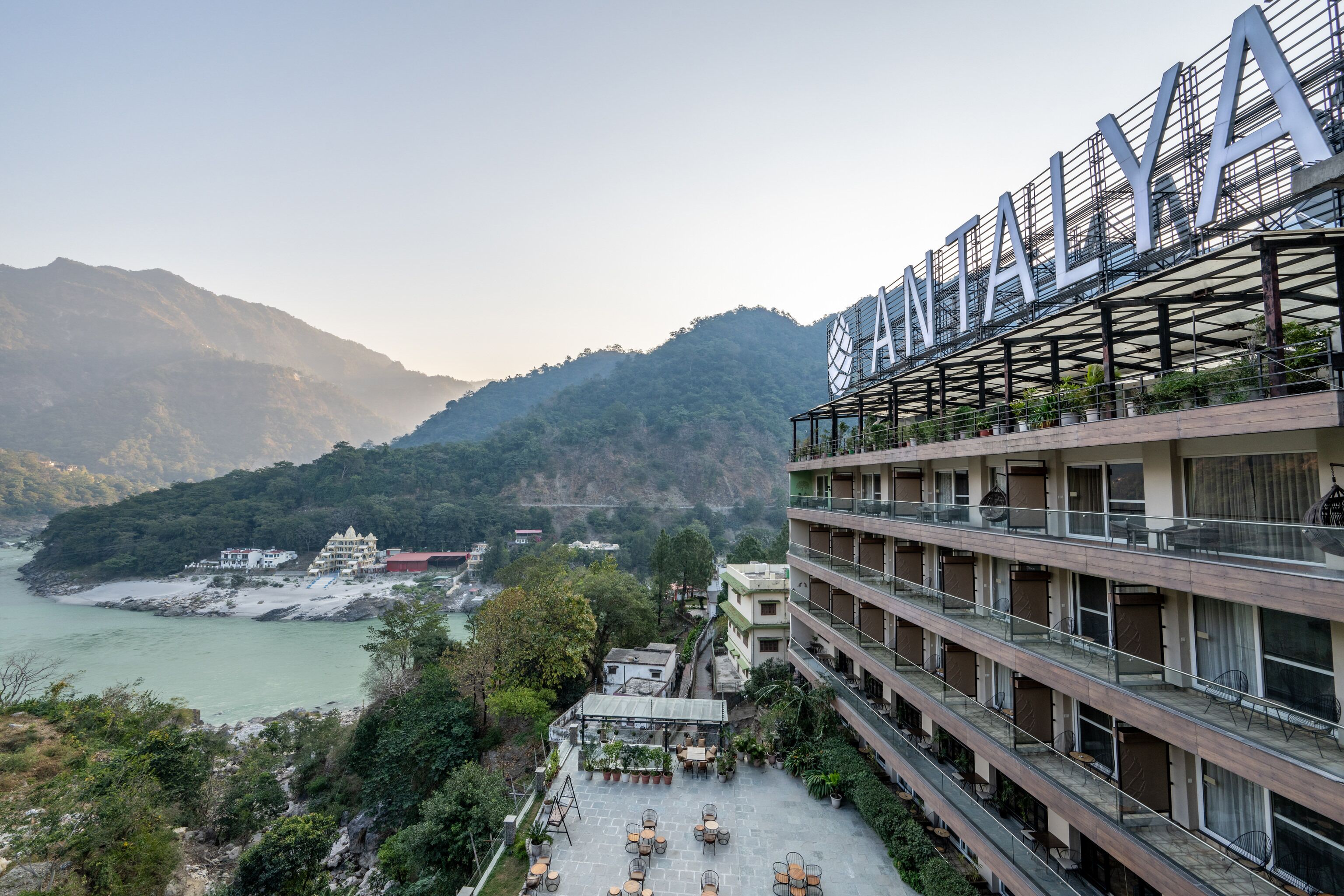Un hotel con varios balcones que dan a un paisaje montañoso y una masa de agua.