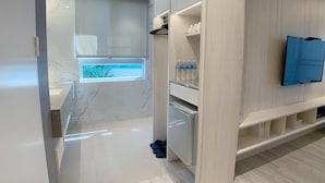 Un baño moderno con tocador de mármol, ducha integrada y ventana que proporciona luz natural.
