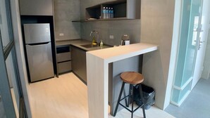 Una cocina moderna con refrigerador integrado, un lavamanos y una barra con taburetes.