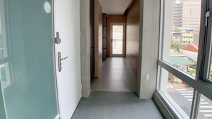 Un pasillo estrecho con una puerta a la izquierda y un ventanal grande a la derecha.