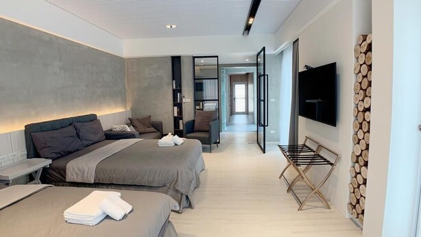 Habitación de hotel moderna con dos camas, televisor de pantalla plana, pared de madera rústica y vista al pasillo.