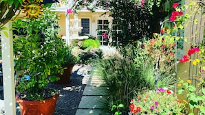 Ein Gartenweg führt zu einem Gebäude mit einer weißen Tür und Fenstern.