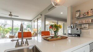 Una cucina moderna con lavello in acciaio inossidabile, una macchina per il caffè e un vaso decorativo con fiori.
