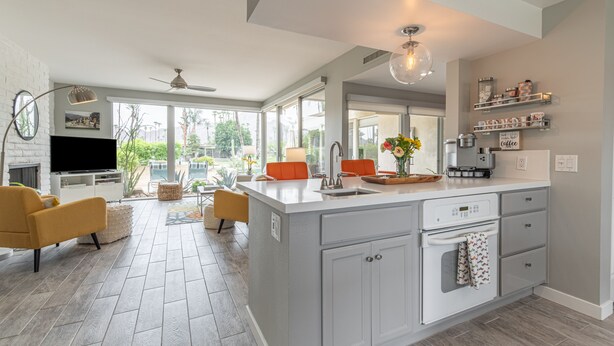 Una cucina moderna con isola centrale, forno integrato e un'ampia finestra che si affaccia su un giardino.