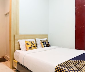 A bed with white bedding, two pillows with geometric patterns, and a blue and yellow blanket. - Hotel O Al-ghani 2 Syariah (Padang)